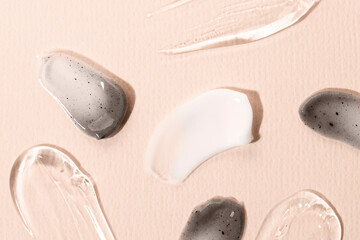 Cosmetic texture on a beige background macro. Smears of cosmetic cream and clear liquid gel, charcoal face mask.