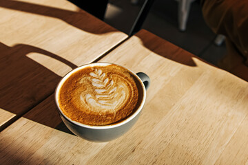 Cup of cappuccino on the wooden table in the morning light