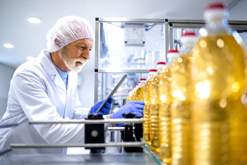 Food industry expert working in vegetable oil bottling factory controlling process of production.