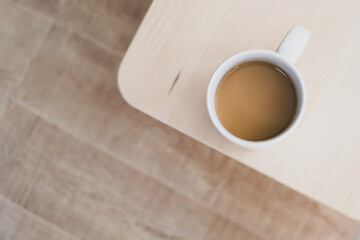 White cup of hot coffee on wooden table, soft focus.