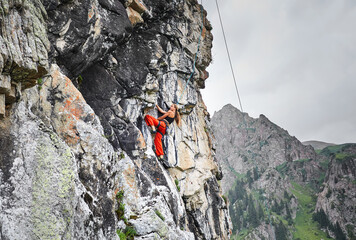 Woman athlete climbing on the high rock in the mountains