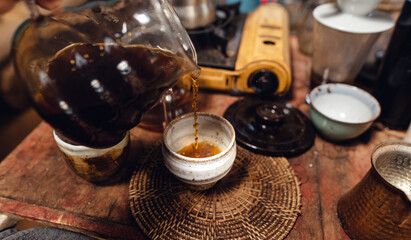 Man pouring hot water on ground coffee with paper filter to making a drip coffee