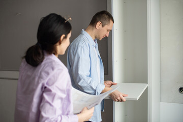A married couple is studying the instructions and trying to assemble new furniture.