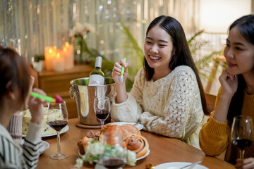 Cheerful friends enjoying home Birthday holiday party. Asian Friends cheering drinking red wine celebrating New Year party.