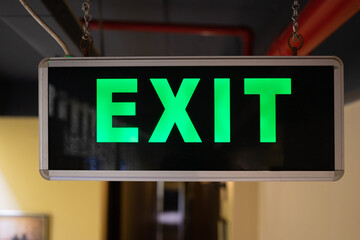 A light box with the green inscription EXIT hangs in a hostel corridor. Exit sign
