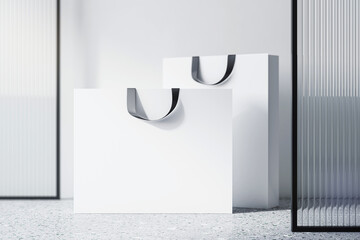 Front view on blank white paper shopping bags with space for your brand name or text on concrete...