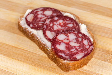 Open sandwich with smoked-cured sausage and butter close-up