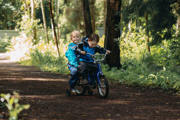 Fototapeta na wymiar Two little caucasian boys are cycling togerther on one bicycle. Image with selective focus
