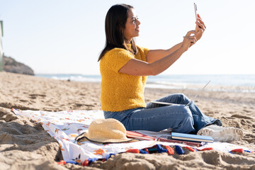 Freelance latin woman taking a selfie on the beach on a work day in Spain. 