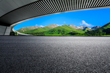 Asphalt road and bridge with green mountain background in Xinjiang, China.