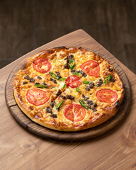 Pizza slice with tomatoes, cheese and minced meat. Pizza is cut into slices on wooden board, on wooden table. Italian Cuisine. Fast food. Wooden background. Close-up. Top view. Copy space. 