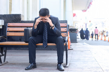 Young businessman sitting on chair, thinking about company, feeling sad and upset, getting bad news from office.