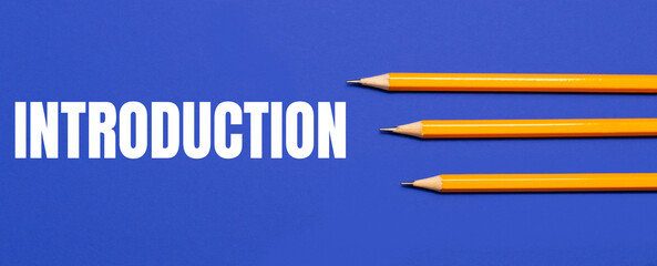 Photo of three orange pencils on a blue background with the text INTRODUCTION - obrazy, fototapety, plakaty