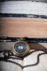 Old vintage books and a watch.
Antique pocket watch on opened old book on background.