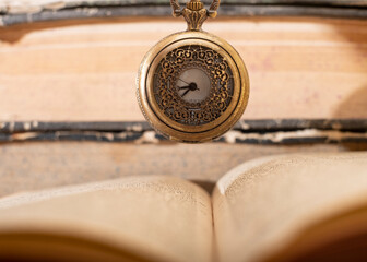 Old vintage books and a watch.
Antique pocket watch on opened old book on background.