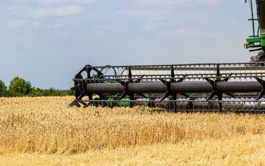 Photo of combine harvester that is harvesting wheat with dust straw in the air