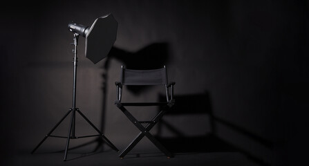 Black Director chair and studio light on black background.