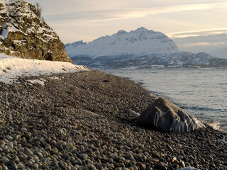 Pebble beach and snowy landscape in Northern Norway