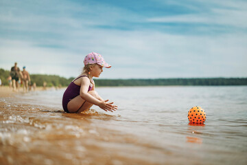 cute little girl playing with rubber ball in sea