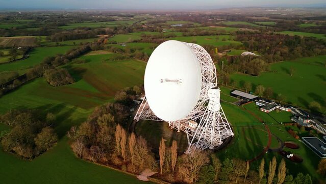 Jodrell Bank Lovell telescope (world&rsquo;s 3rd largest) on a winter&rsquo;s late afternoon, UNESCO World Heritage Site, Cheshire, England, UK - medium aerial drone anti-clockwise pan, front to rear 04.02.23