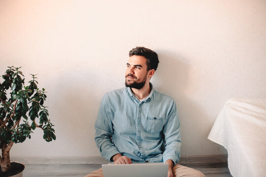 Happy Businessman Using Laptop Computer While Sitting On Floor At Home