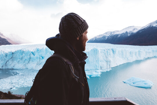 Male traveler near glacier on cloudy day