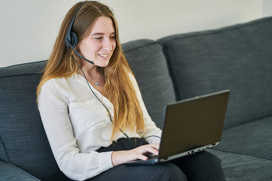 Young executive in work clothes and with headphones and laptop working from the living room of your home.