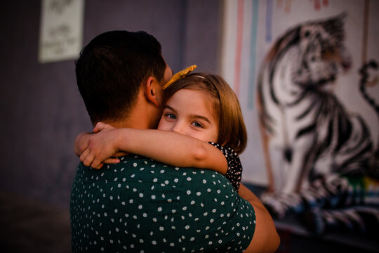 Father Hugging Daughter as Daughter Peers Over Shoulder