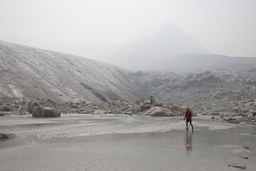 Hiker explores ablation zone below glacier.