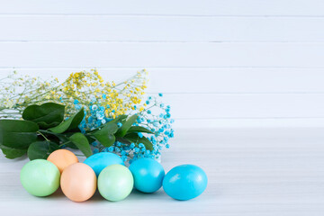 Happy Easter. Congratulatory easter background. Easter eggs and flowerson white table.