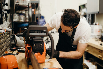 Man in workshop fixing chainsaw