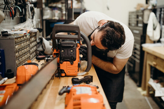 Man in workshop fixing chainsaw