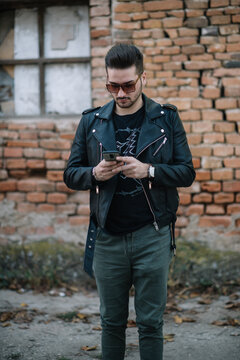 Guy with sunglasses standing on the street and using mobile phone.