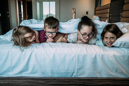 siblings laying on bed facing forward in hotel room