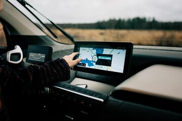 young boys hand pointing at a GPS sat nav map in an electric car