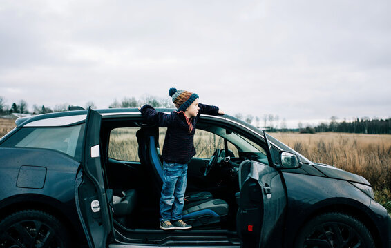 young boy standing on an electric car looking out at the countryside
