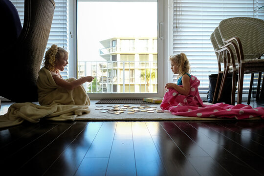 little girls sitting on floor in blankets playing cards in backlight