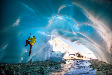 Man ice climbing in ice cave during luxury adventure tour.