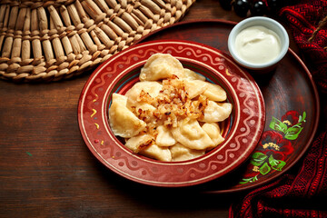 Traditional Ukrainian varenyky stuffed with potato and fried onions in clay dishes. Ukrainian cuisine. Close up