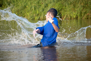 Asian boy is spending his freetimes by diving, swimming, throwing rocks and catching fish in the river happily, hobby and happiness of children concept, in motion.