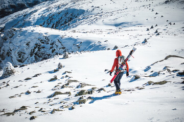 Ski mountaineer walking through frozen snow field on mountain