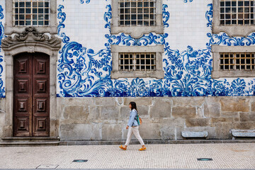 Tourist walking, azulejos tiles over Chapel Of Souls, Porto, Portugal - obrazy, fototapety, plakaty
