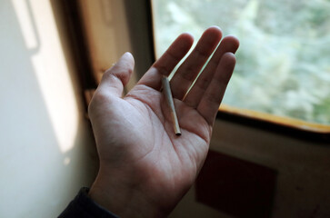 A smoking joint on a hand, out of focus back ground. I shot this picture on a train.
