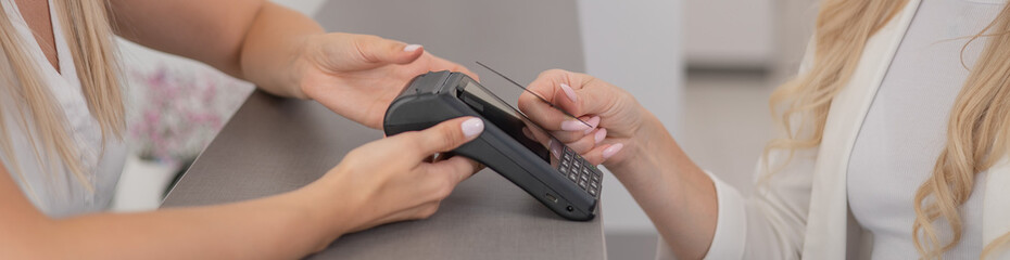 Woman paying with credit card using NFC contactless payment. Widescreen.