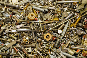 Background of screw bolts, nuts, many screws. A set of screws, bolts, nuts and other homemade fasteners. Slight sharpness of roughness, possible graininess. Shallow depth of field, soft selective focu