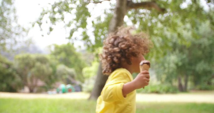 Smiling African American boy happily having an ice cream on a sunny day in the park