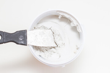 putty knife on tub of white acrylic glazing putty