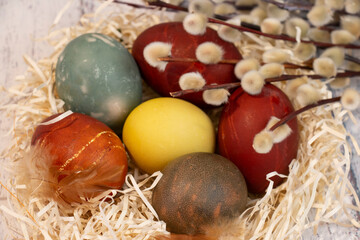 Fototapeta na wymiar Painted colorful Easter eggs on the table in a mini nest. Simal of Easter