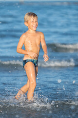 Fototapeta na wymiar Nice cute little boy in the sea making splashes