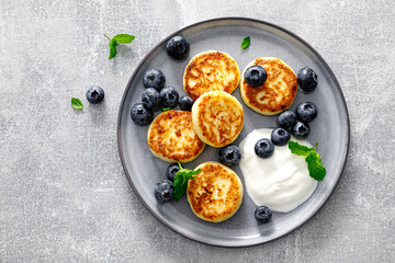 Cottage cheese fritters with fresh blueberry and yogurt for breakfast, copy space, view from above